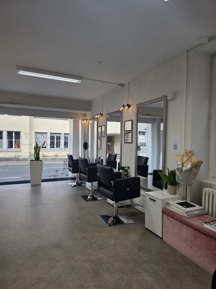 Espace coiffage lumineux avec grands miroirs et banquette rose du salon Beauty Time